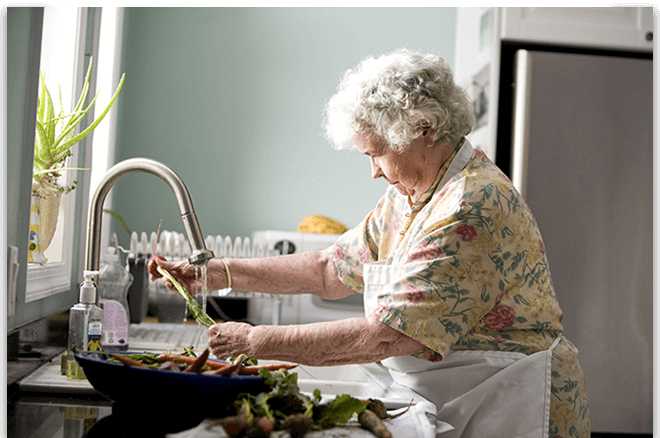 Dame âgée autonome qui prépare le repas qui bénéficie d'une aide ménagère sociale